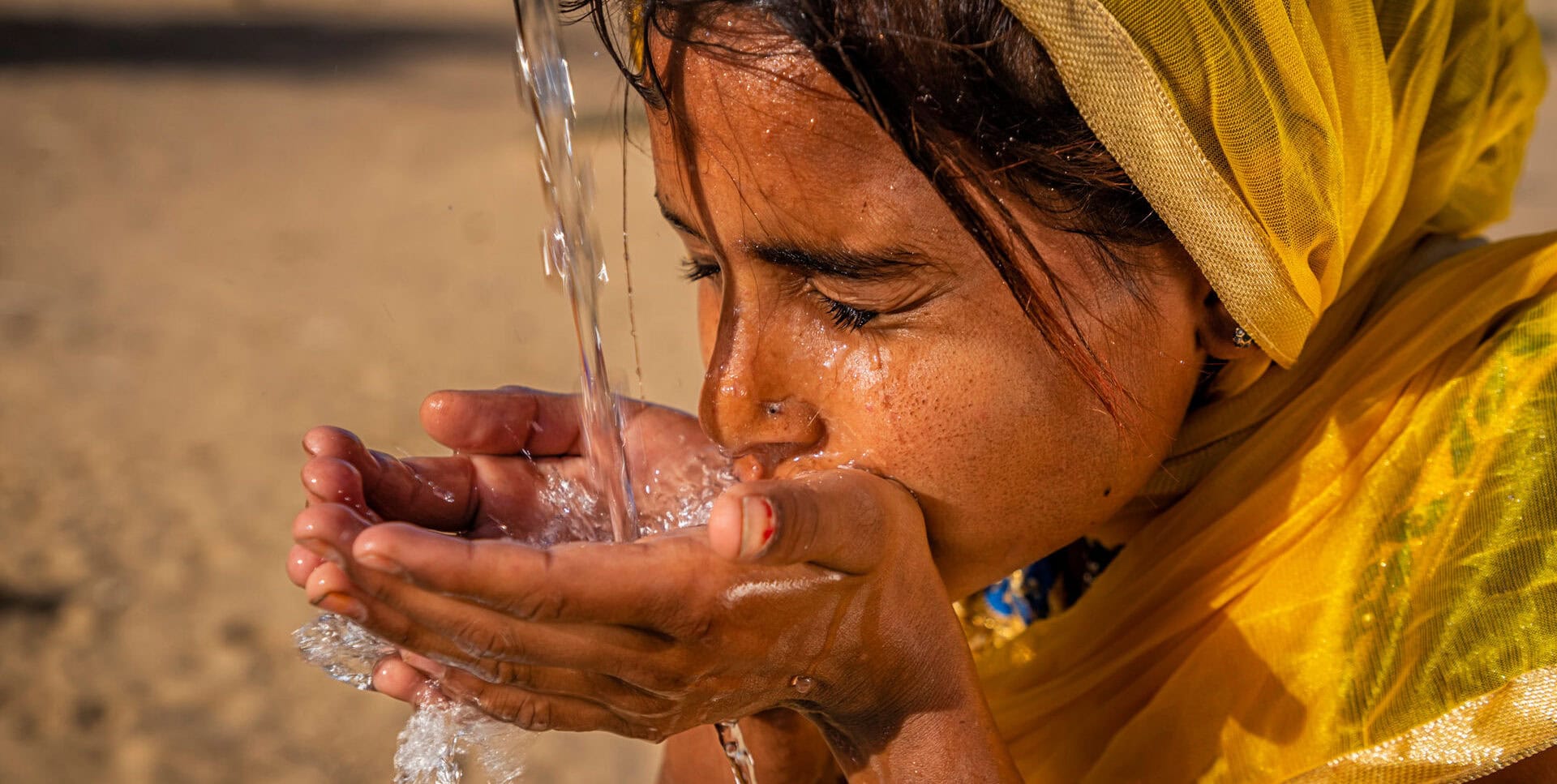 Indian young girl drinking fresh water, desert village, Rajasthan, India - Slider