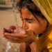 Indian young girl drinking fresh water, desert village, Rajasthan, India - Slider
