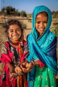 Indian little girls drinking fresh water, desert village, Rajasthan, India